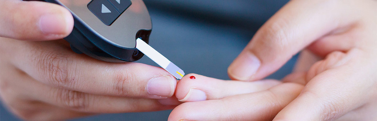 Ein Diabetiker nimmt mit einem Teststreifen einen Tropfen Blut von seinem Finger auf, um seinen Blutzucker zu messen