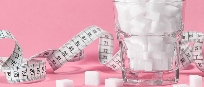 Maßband und Würfelzucker stehen symbolisch für Diabetes Typ 2, der häufig durch falsche Ernährung und Übergewicht ausgelöst wird