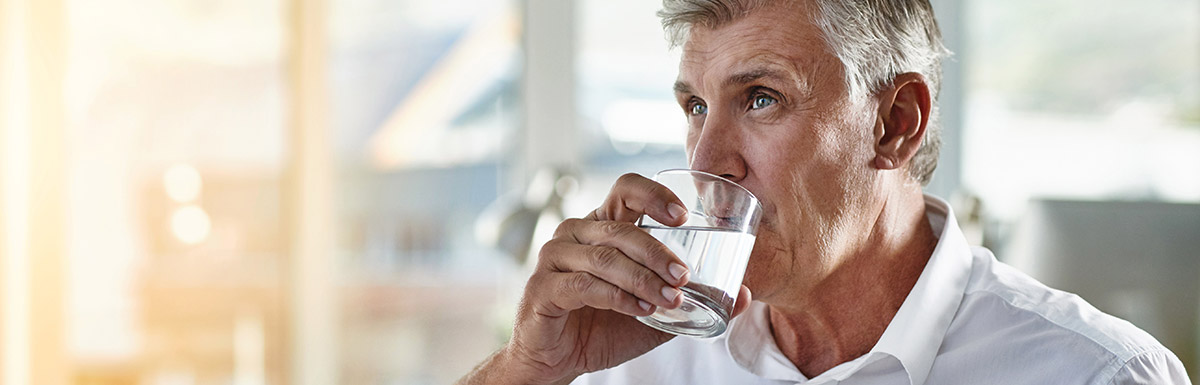Älterer Mann trinkt aus einem Wasserglas. Vermehrter Durst kann zu den Diabetes-Symptomen gehören.
