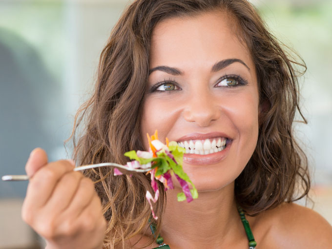 Junge brünette Frau isst einen Salat und meistert ihr Leben mit Diabetes