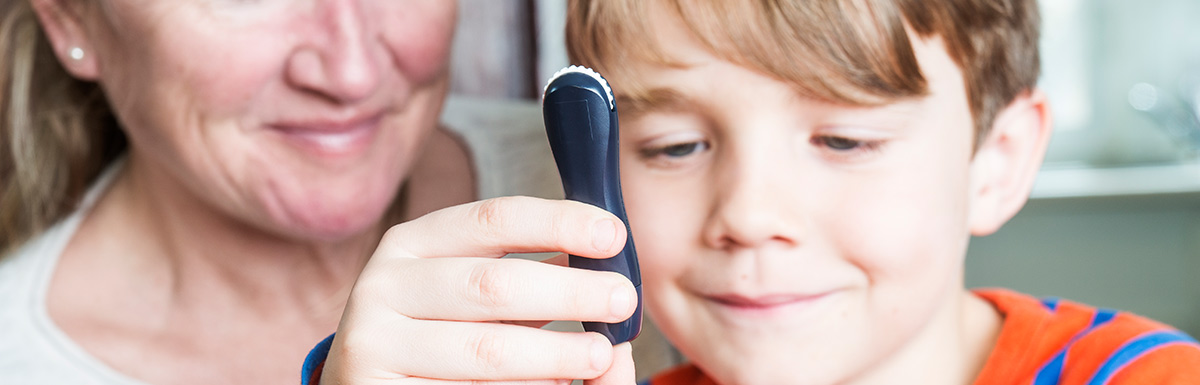 Nahaufnahme Kinderhand: Kind, das einen Blutzuckertest am eigenen Finger durchführt.