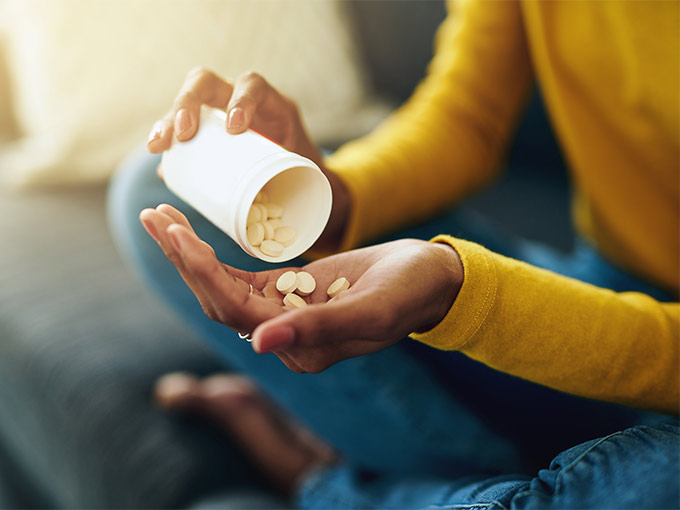 Frau hält einen Behälter mit Tabletten in der Hand - cortisonhaltige Tabletten stehen in Verdacht, Diabetes zu begünstigen.