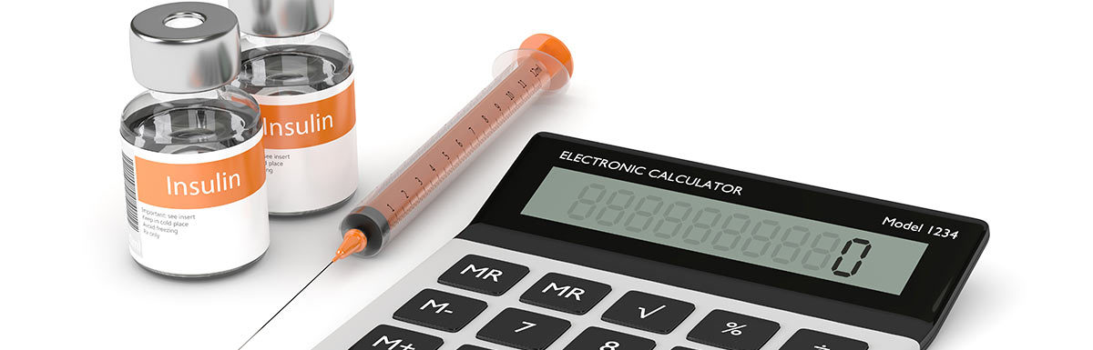 Ein Taschenrechner liegt neben einer Spritze und Insulin-Ampullen. Den HbA1c zu berechnen ist für Diabetespatienten wichtig.