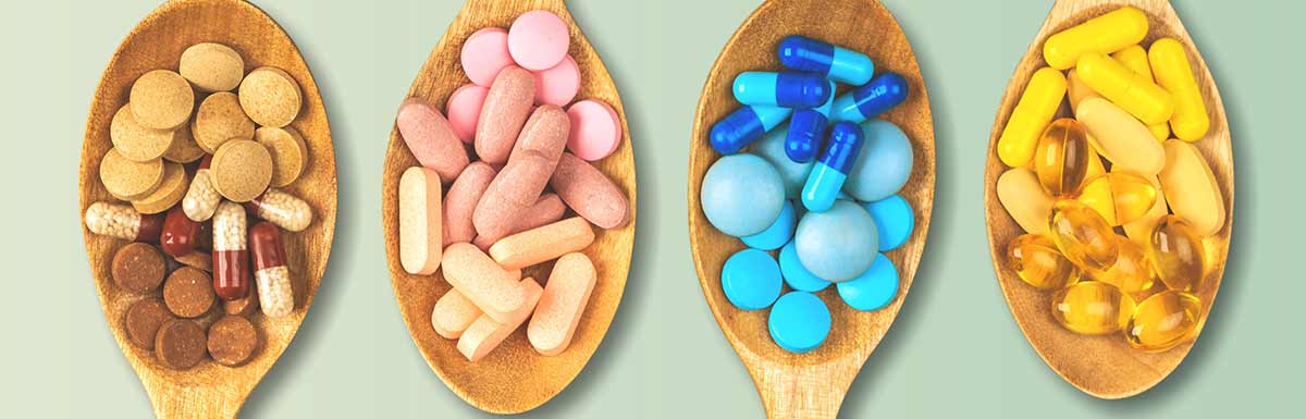 Verschiedenfarbige Pillen auf Holzlöffeln - Nahrungsergänzungsmittel können bei Diabetes sinnvoll sein.