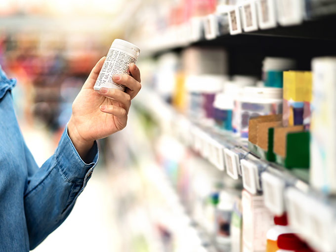 Mann steht vor einem Supermarktregal und inspiziert eine Tablettenverpackung: Bei Diabetes werden Nahrungsergänzungsmittel oft zur begleitenden Therapie eingesetzt.