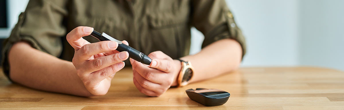 Eine junge Frau sticht sich in die Fingerkuppe, um ihren Blutzucker zu messen: Ein niedriger Blutzucker gehört zu den Symptomen bei Diabetes mellitus Typ 3.