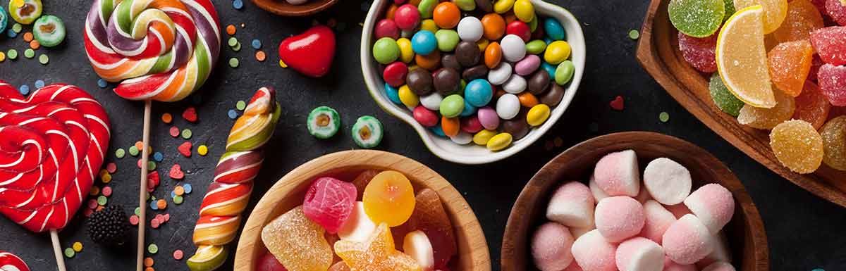 Ein Tisch voller bunter Süßigkeiten - für die Behandlung einer Unterzuckerung dürfen Diabetiker*innen auch zu zuckerhaltigen Speisen greifen.