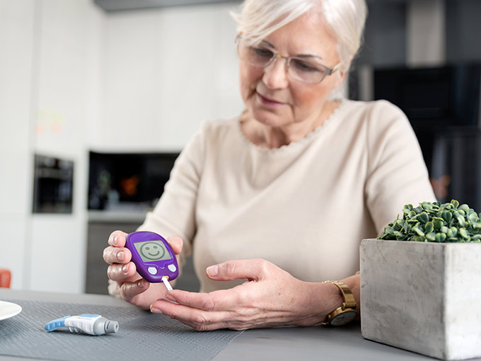 Ältere Frau misst ihren Blutzucker: Glycowohl-Studien belegen die Wirksamkeit des Arzneimittels bei Diabetes.